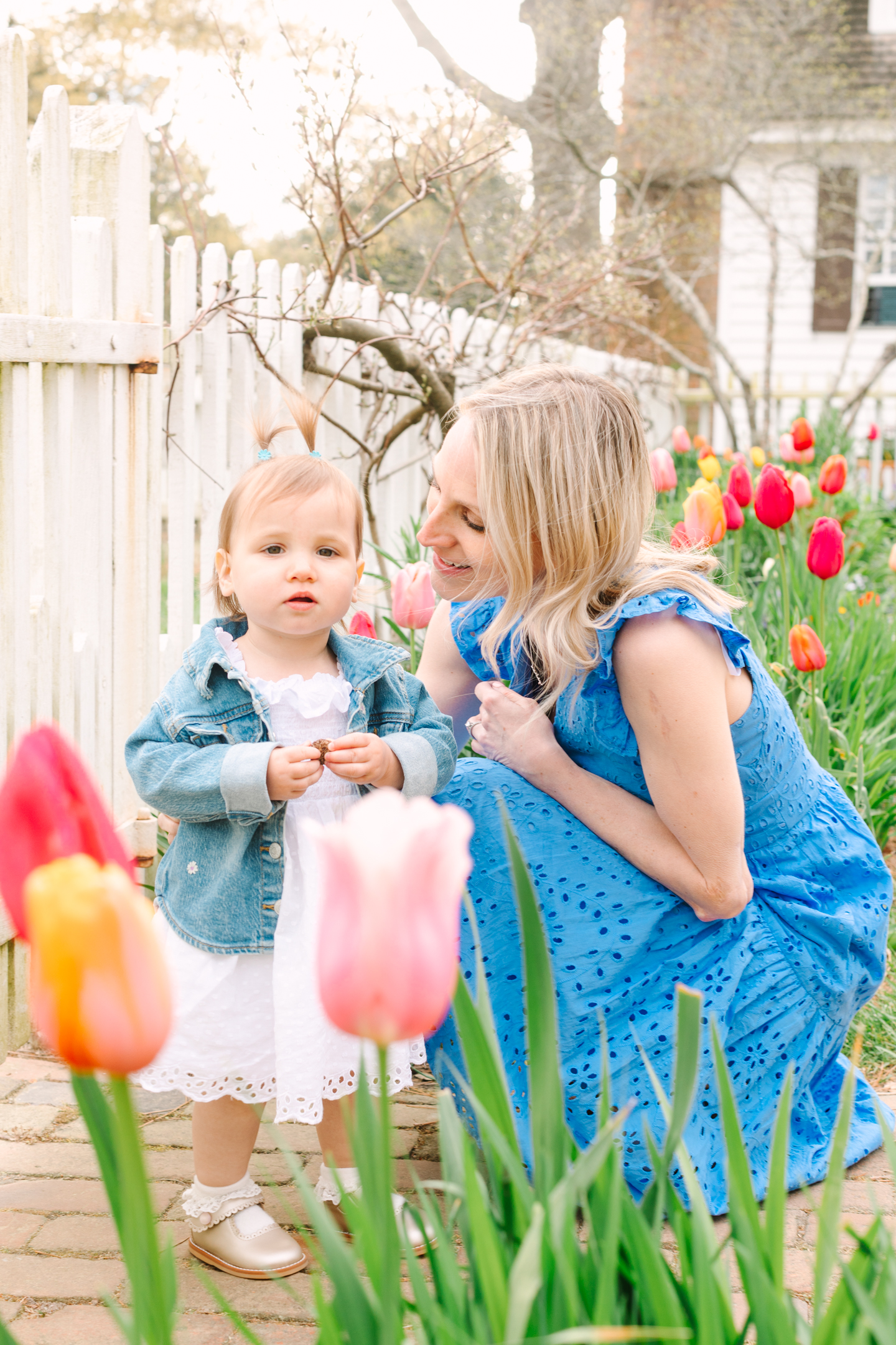 Mom and daughter smiling together in a colorful tulip garden during a Williamsburg spring mini session