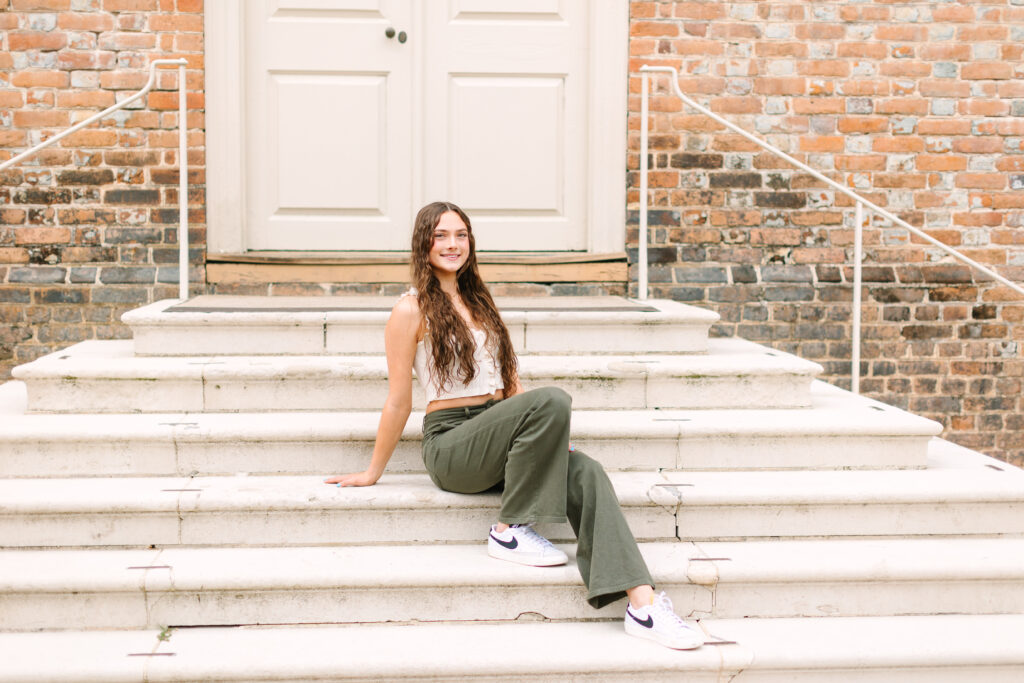 Senior portrait on the stone steps of a historic building at William & Mary in Williamsburg, VA, with soft natural light and a classic feel.