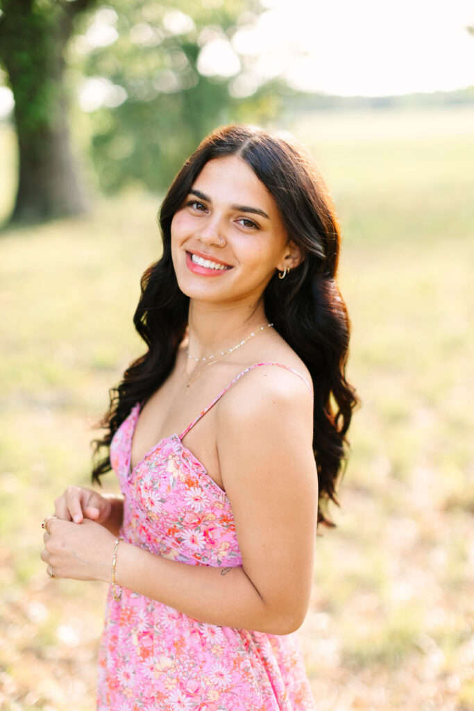 Close-up senior portrait during golden hour, with warm light and beautiful pink spring dress
