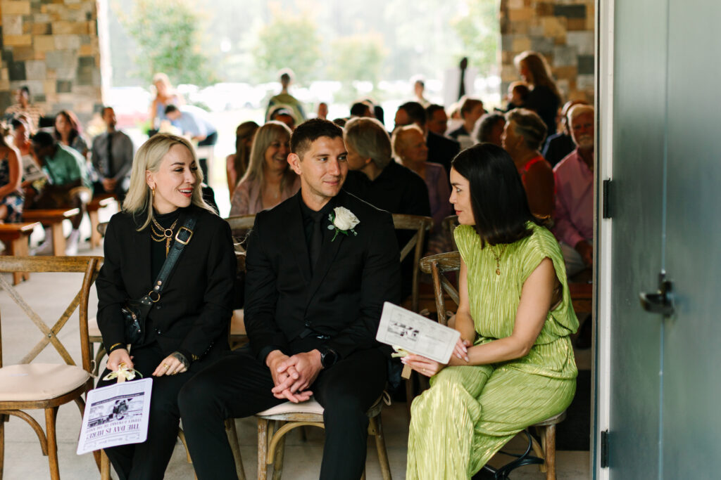 Guests before ceremony holding wedding paper fan designed as a newspaper detail at The Maine of Williamsburg