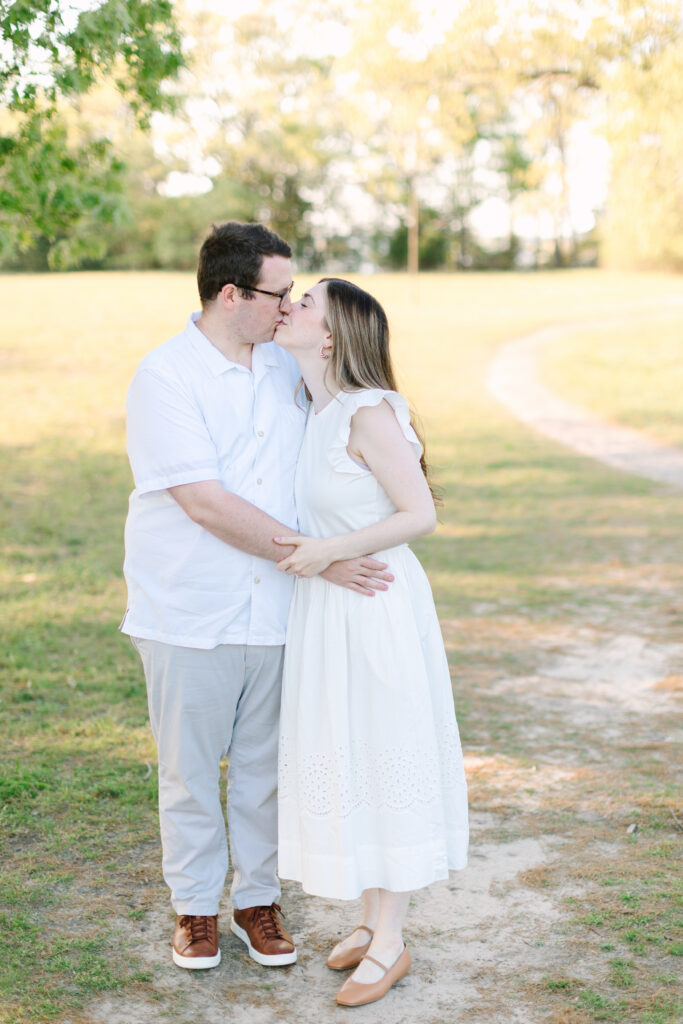 Husband and wife sharing a kiss during family photos at a Yorktown Summer Mini Session in Yorktown, Virginia.